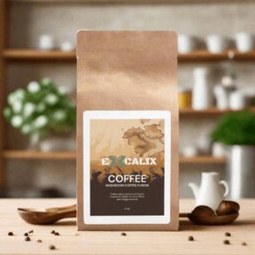 A brown paper bag of Excalix mushroom coffee is displayed on a wooden table in a cozy kitchen setting. The label on the bag features the Excalix logo and reads "Excalix Coffee, Mushroom Coffee Fusion." The background includes blurred kitchen elements such as jars and a coffee pot, creating a warm and inviting atmosphere